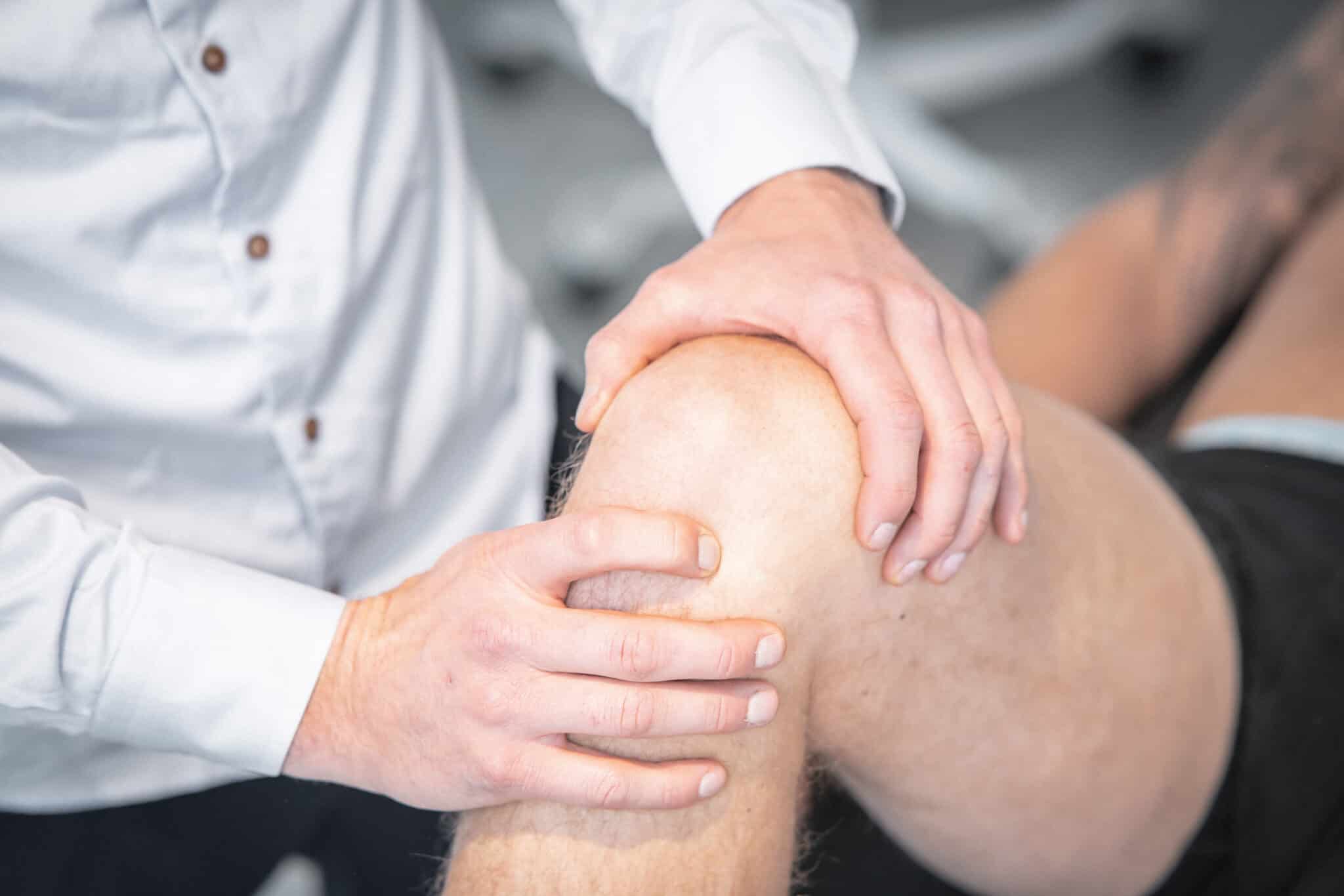 Professionel behandler undersøger en patients knæ for smerter ved bøjning under en klinisk behandling med fokus på led og bevægelighed.