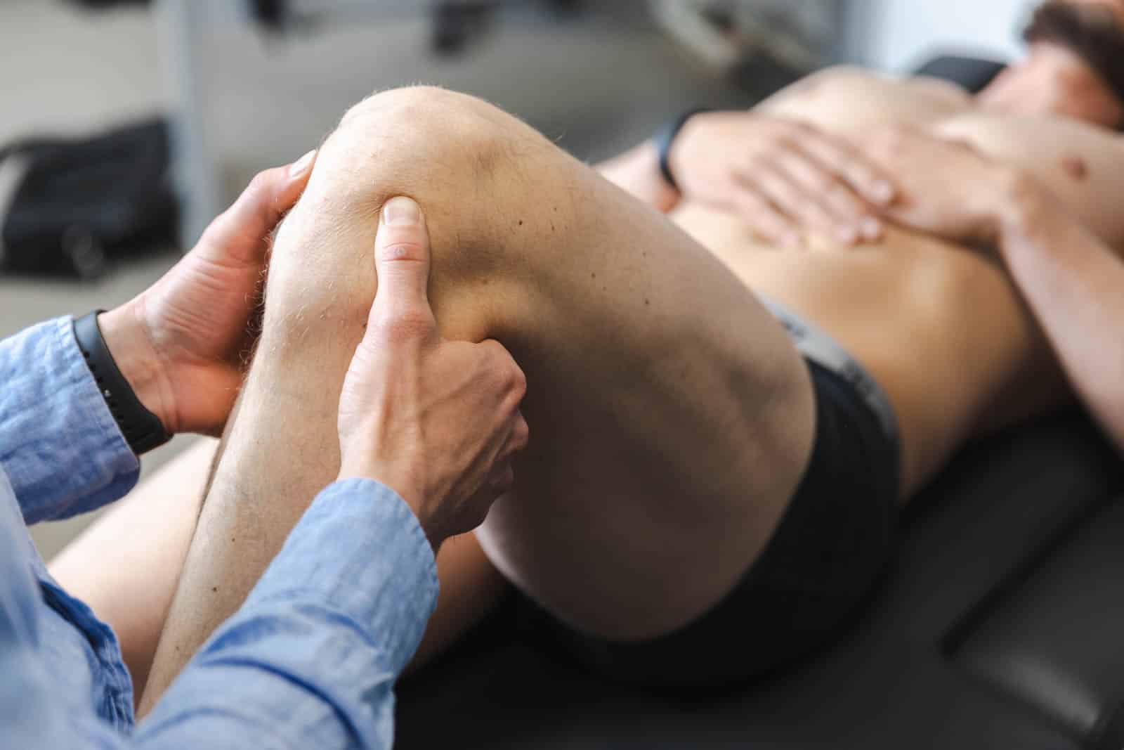 Behandling af smerter i knæet hos osteopat – mand får manuel terapi på briks.