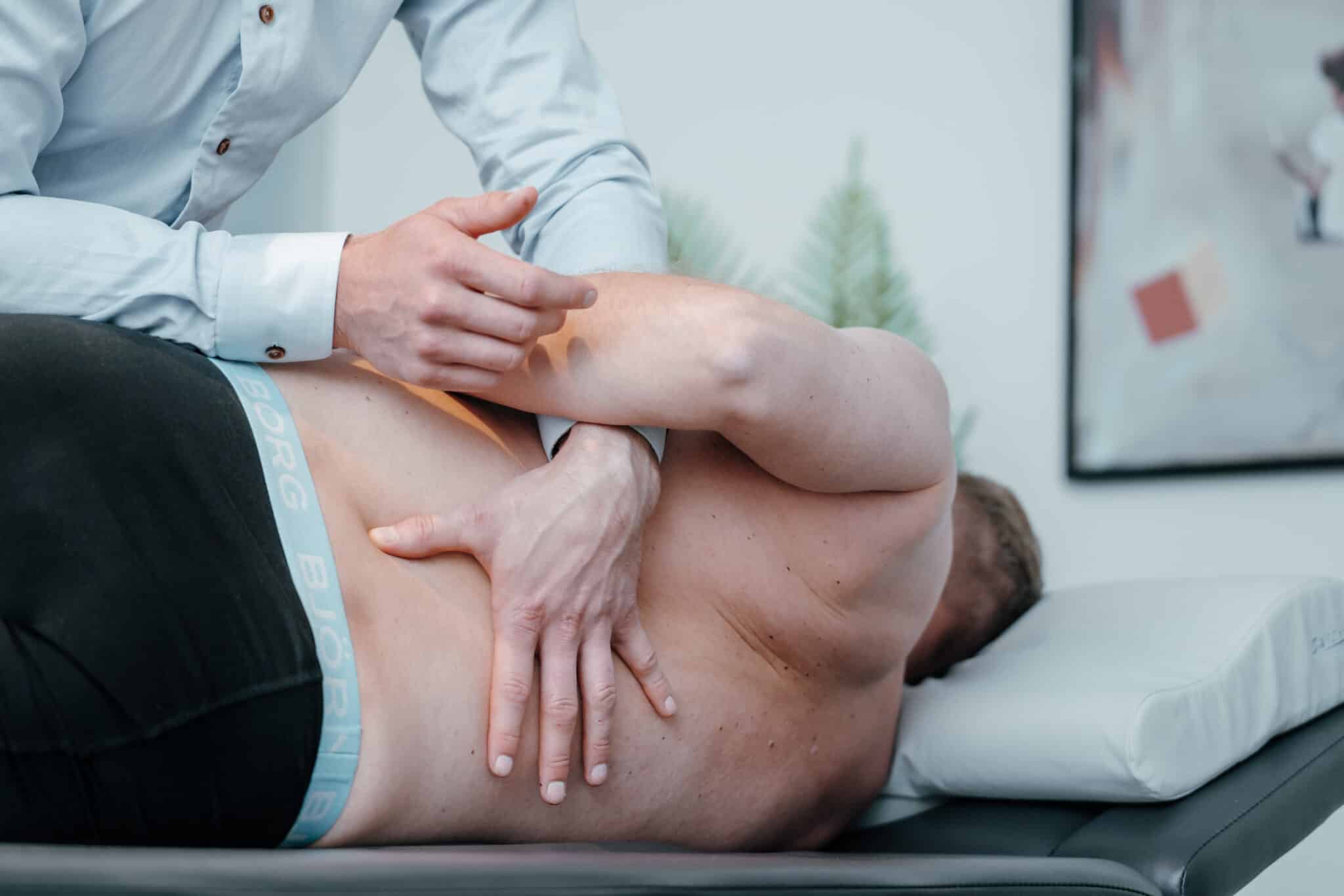 Patient ligger på briks og får manuel behandling af kiropraktor mod smerter i lænden og ned i benet.