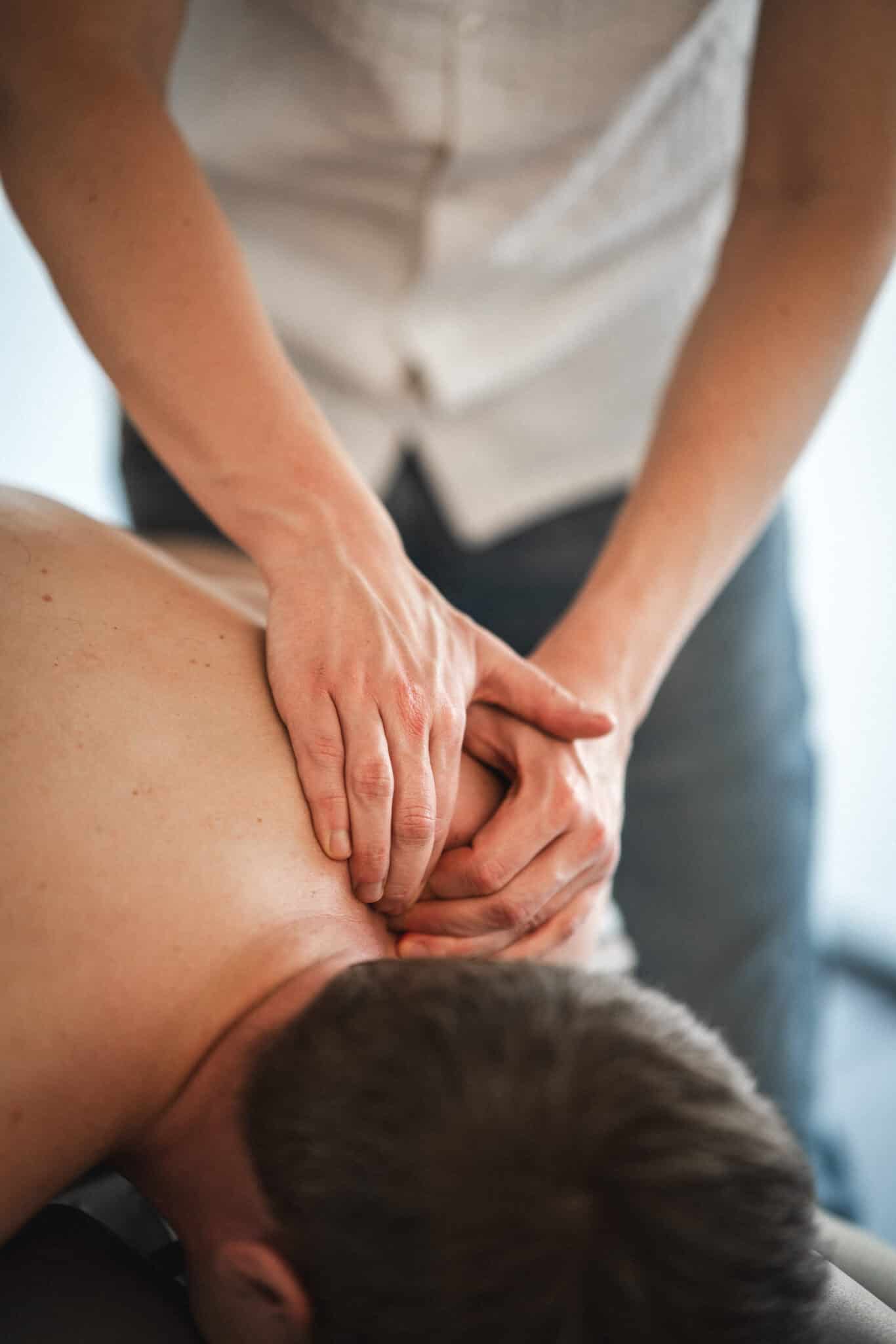 Fysioterapeut masserer patientens skuldre og nakke som behandling, der viser, at myoser kan masseres væk.