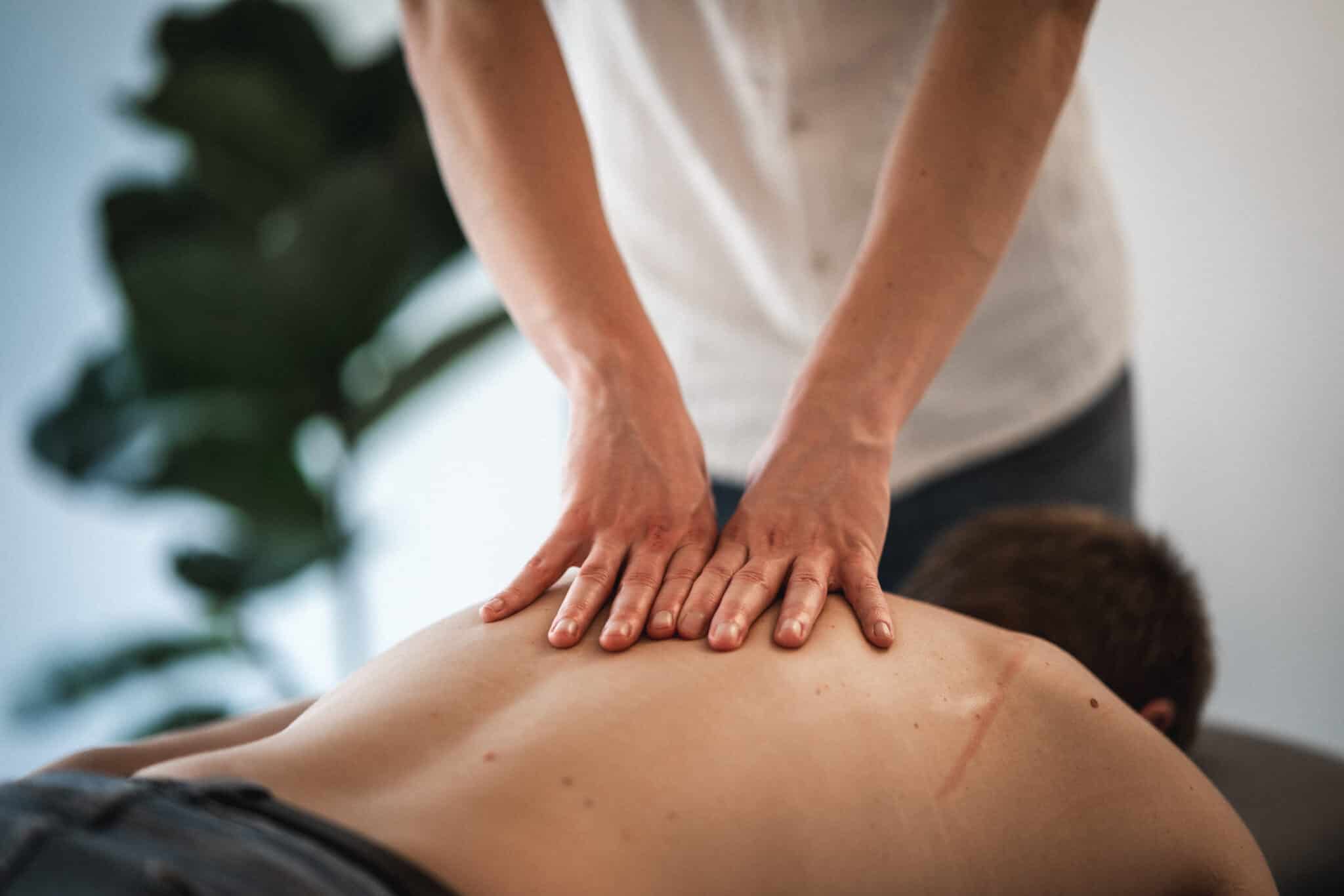 En terapeut udfører dybdegående massage på en ryg for at løsne spændinger og reducere ømme muskler efter overbelastning.