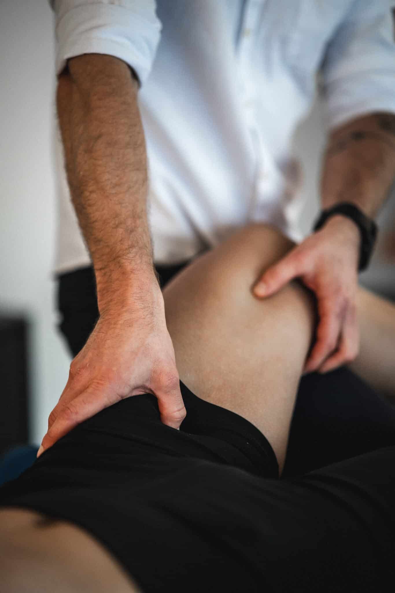 Terapeut udfører manuel behandling på patient med muskelspændinger – behandling af smerter i benene.