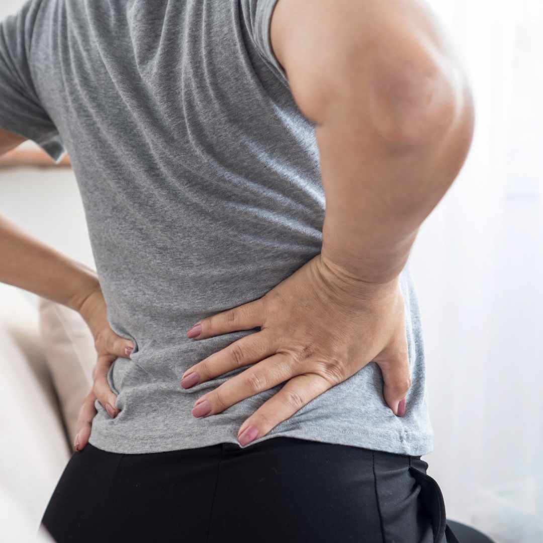 Ældre person med hænderne på lænden på grund af stive led og spændinger i kroppen.