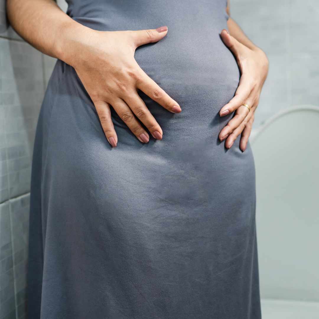 Person holder sig til maven med hænderne på grund af oppustethed og ondt i maven.