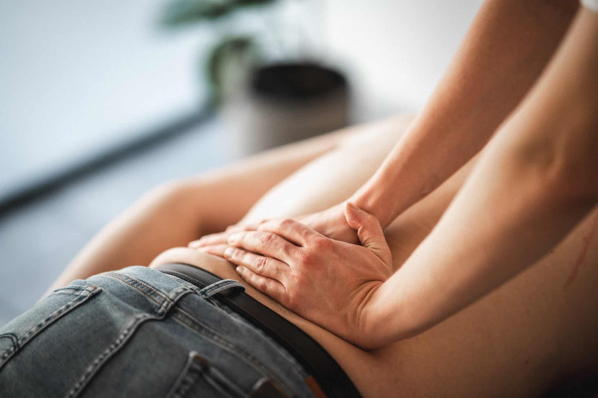 Manuel behandling af halebenssmerter med tryk på nederste del af ryggen.