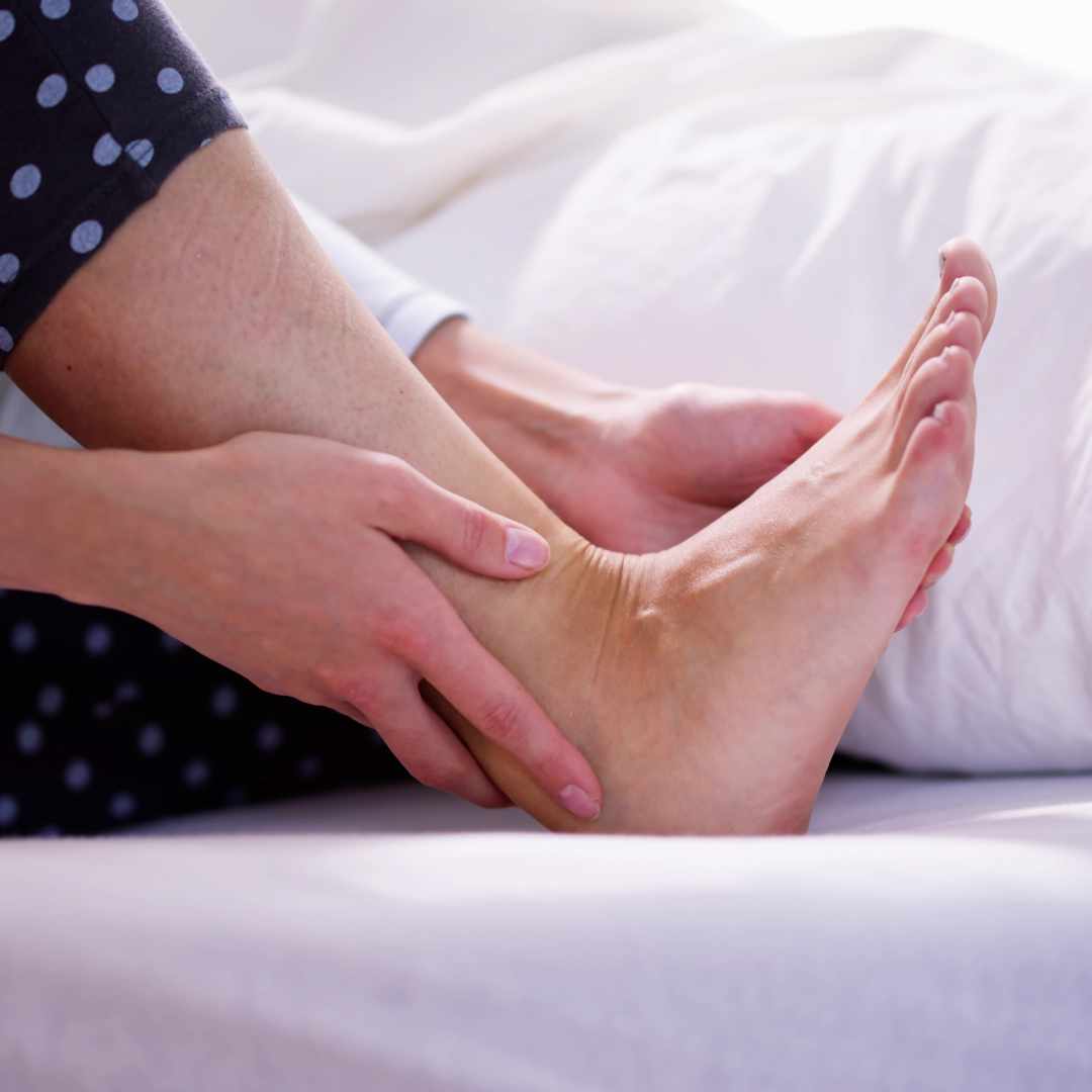 Kvinde holder om hælen på grund af smerter i foden.