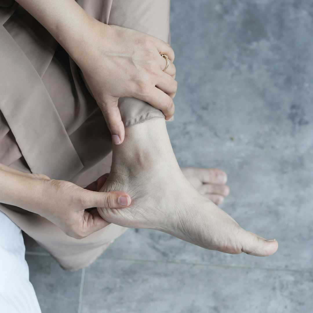 Person tager sig til anklen som tegn på smerter i foden.