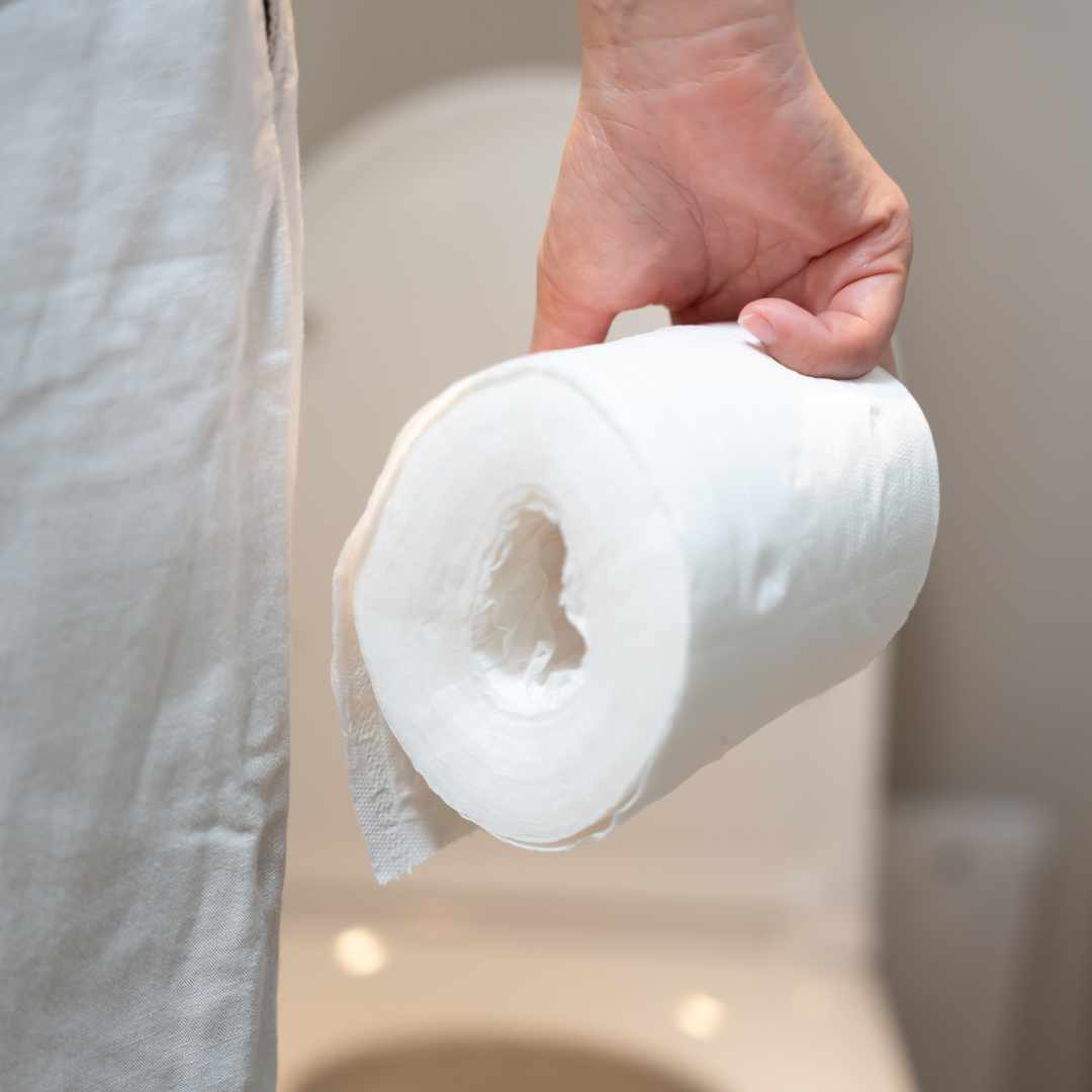 Person holder toiletrulle som symbol på diarré og hyppige toiletbesøg ved maveproblemer.